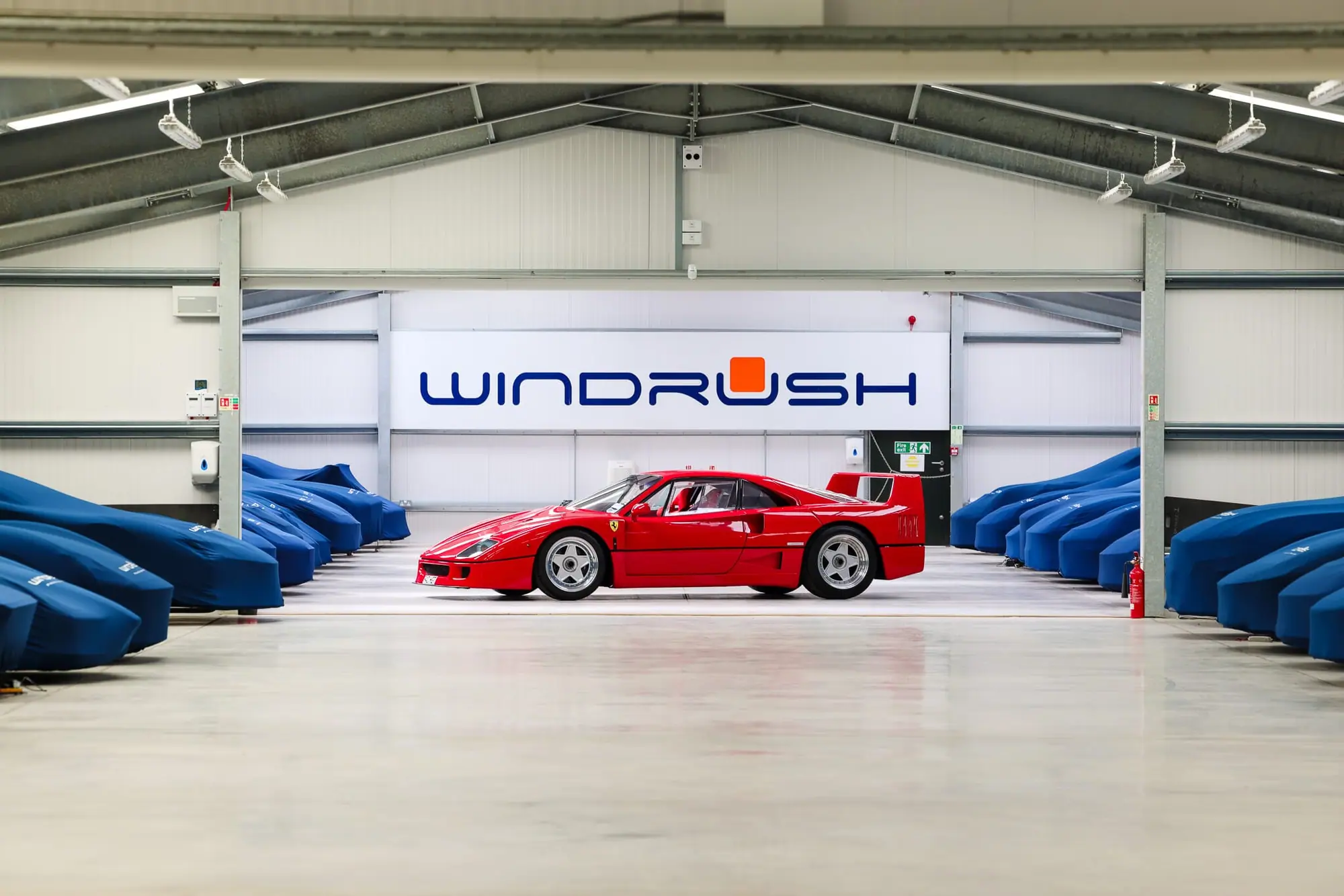 A red Ferrari F40 in front of covered cars